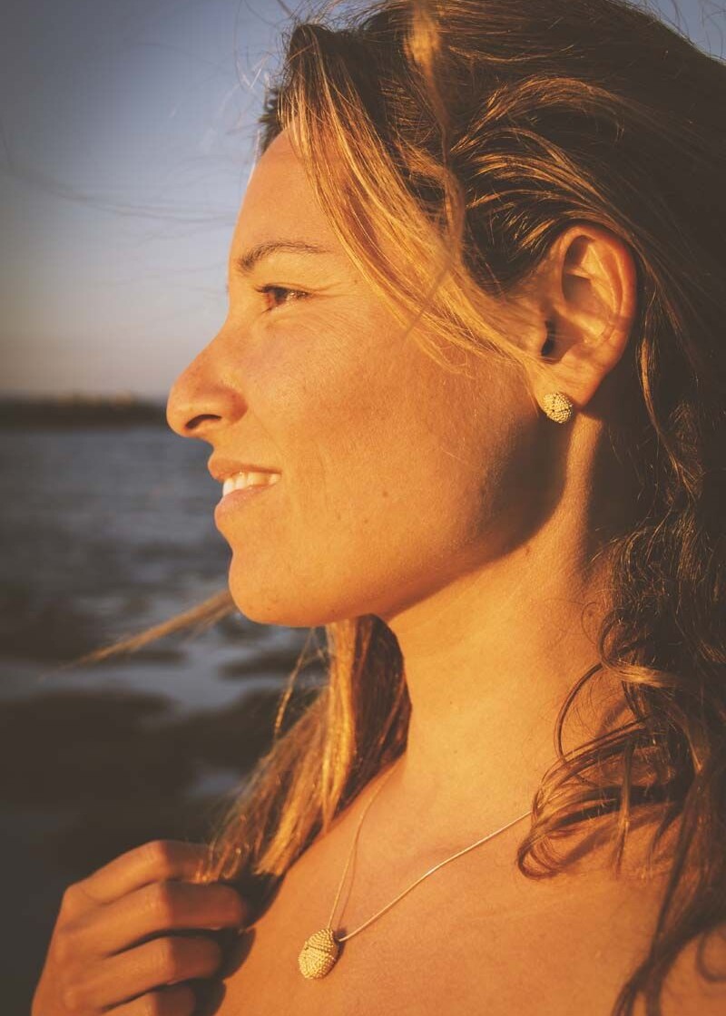 mujer con pendientes y collar "Erizos de mar dorados" en oro vermeil con el mar de fondo